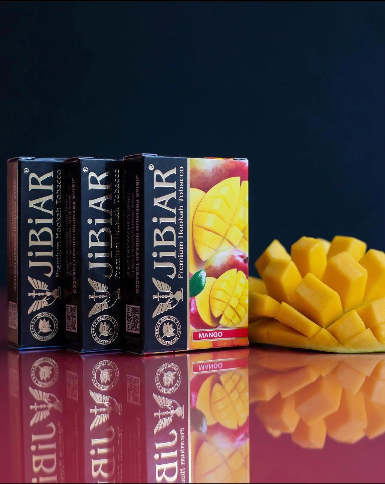 JiBiAR boxes with mangoes on a reflective surface and dark background